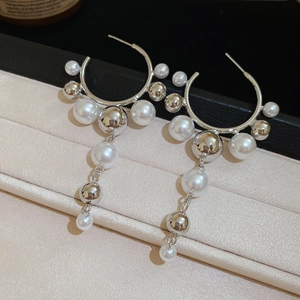 Detail of silver needle C-shaped earrings with alternating pearls and metallic beads