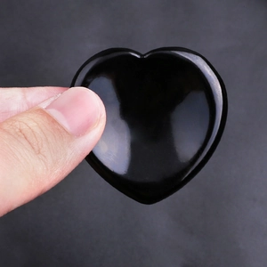 Macro shot of a smooth heart-shaped black obsidian thumb stone for stress relief and healing