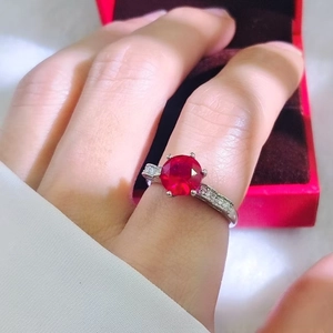 Macro shot of 2-carat red ruby ring in silver 4-prong setting with side diamond accents
