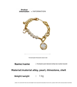 Close-up of gold bracelet featuring freshwater pearls, a number 5 charm, and a pavé smiley face