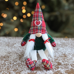 Festive Christmas Gnome doll in red plaid sit on snow with warm bokeh light background