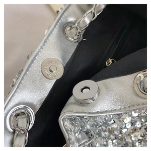 Detail der silbernen Pailletten-Beuteltasche mit Magnetverschluss und Metallkette