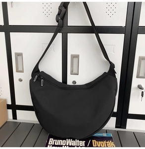 Detail of black nylon crescent crossbody bag with adjustable strap and zip closure