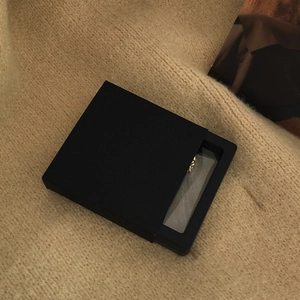 Detail of a matte black drawer-style jewelry box with a transparent display window