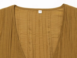 Detail of V-neckline on ginger yellow pleated set showing vertical crinkle texture