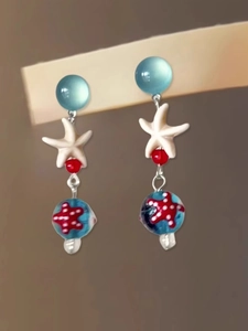 Dettaglio ravvicinato di orecchini a forma di stella marina con perle blu e bianche e ceramica