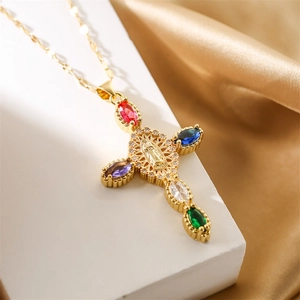 Vue macro du pendentif croix dorée avec zircons colorés et camée religieux détaillé