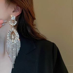 Macro detail of luxury long tassel drop earrings with sparkling crystals on model