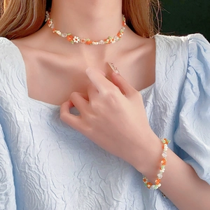 Close-up of handmade white orange and green beaded necklace with flower charms