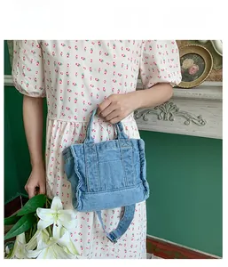Close-up of light blue washed denim handbag held by a model in a retro vintage setting