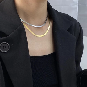 Close-up of gold and silver flat snake bone chain necklaces layered on a model's neck