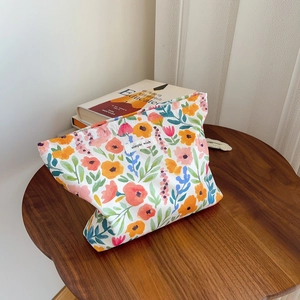 Detailed view of floral canvas makeup bag with vibrant prints and woven texture