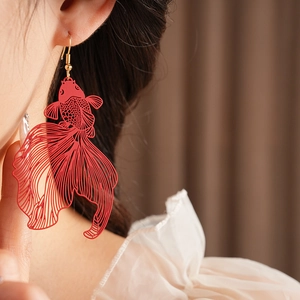 Vue latérale d'une boucle d'oreille carpe koi rouge portée par un mannequin chic
