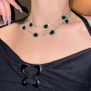 Macro shot of double-layer silver necklace with square green gemstones and pavé crystals