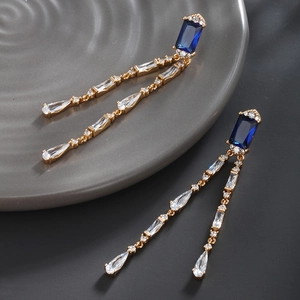 Macro shot of long drop earrings featuring deep blue gemstones and cubic zirconia crystals