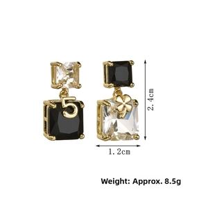 Detail of asymmetric cube crystal earrings with number five and clover in gold finish