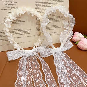 Detail shot of white lace headbands with delicate floral accents and long ribbon streamers
