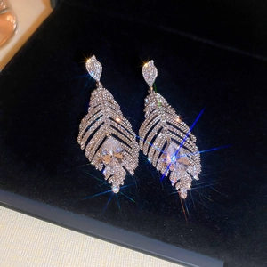 Gros plan de boucles d'oreilles plume en argent avec zircone sur velours noir