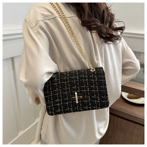 Detail of black tweed crossbody bag with gold chain strap shown on model's back