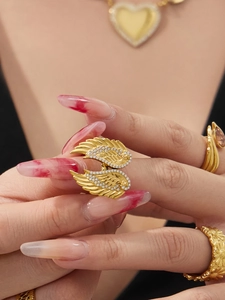 Close-up of a golden double wing ring with sparkling inlaid zircon on a finger