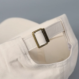 Detail of adjustable cotton strap and bronze buckle on off-white baseball cap