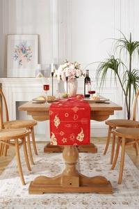 Detail of red table runner with golden clouds and lanterns on a wooden dining table