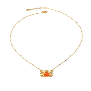 Gros plan du collier avec pendentif crabe doré serti d'une pierre précieuse orange