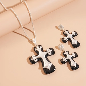 Detail of dark gothic cross necklace and earrings with silver carvings and black resin