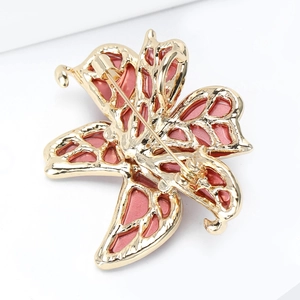 Elegant gold-tone butterfly brooch with pink enamel wings and a classic safety pin back
