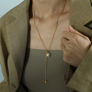 Elegante goldene Y-Perlenhalskette an einem Modell mit khakifarbenem Blazer für Business