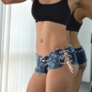 Dettaglio di mini shorts in denim blu scuro con lacci laterali e bordi sfrangiati
