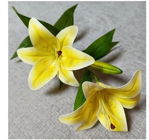 Macro shot of 3D artificial lilies with realistic yellow-white petals and green leaves