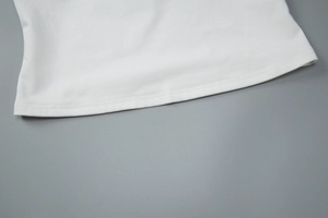 Detailed close-up of the fine double-needle stitching on the white lace camisole hem