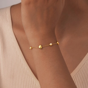Bracelet chaîne en acier doré avec pendentif cœur et zircon porté sur le poignet