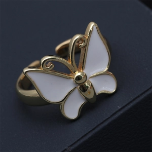 Macro detail of golden butterfly ring with white oil drip finish and adjustable band