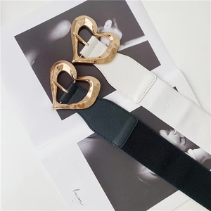 Close-up of golden heart-shaped metal buckles on black and white elastic waist belts