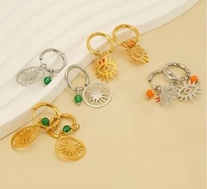 Gros plan de boucles d'oreilles créoles soleil et œil en or et argent avec perles