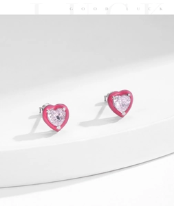 Macro detail of heart-shaped pink crystal stud earrings with colorful enamel borders