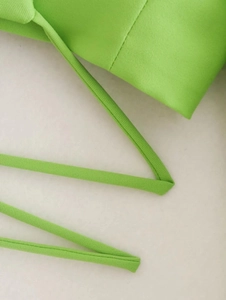 Detail of bright green cropped top featuring delicate thin straps and premium stitching