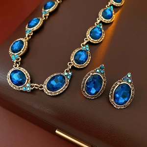 Gros plan d'un ensemble de bijoux vintage dorés avec pierres bleues sur un étui en cuir