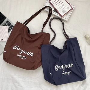 Detail of navy and brown canvas tote bags with Bonjour slogan and leopard print straps