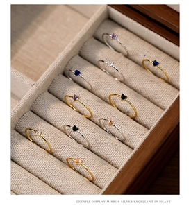 Macro display of mirror-polished silver heart rings with colorful zircon in jewelry box