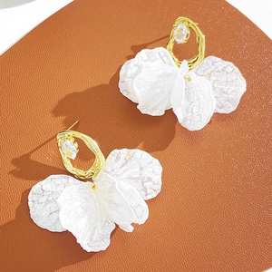 Détail de boucles d'oreilles fleuries avec anneaux dorés et pétales blancs translucides