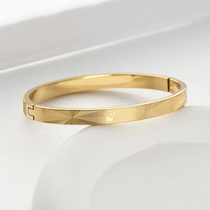 Detail shot of golden titanium steel bangle with radial mesh texture and crown relief