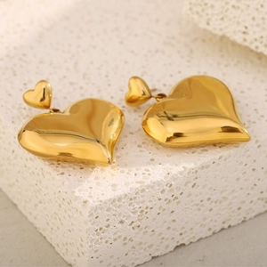 Close-up of double heart 18K gold plated stainless steel earrings on a mineral stone
