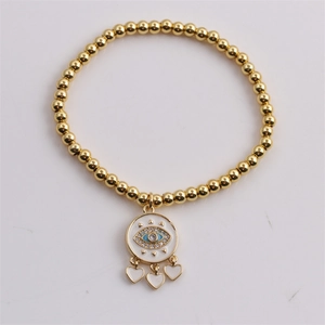 Detail of gold evil eye charm bracelet with three white heart pendants and beads