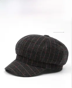 Detailed close-up of dark grey plaid newsboy cap showing wool blend texture and orange checks