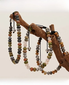 Macro detail of natural stone beaded bracelets with adjustable cord on rustic wood