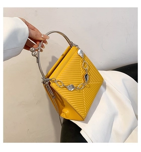Detail of yellow quilted leather handbag with V-shaped stitching and silver metal handle