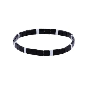 Macro view of minimalist black and white square tila beads on a stretch bracelet